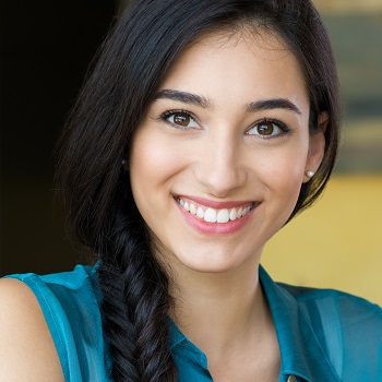 Closeup shot of young woman smiling. Portrait of brunette girl looking at camera and smiling. Shallow depth of field with focus on beautiful young happy girl with braid smiling.